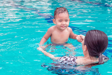 asian mother and baby in swimming pool.  little baby having fun in a swimming pool at thailand