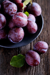 Fresh violet plums at dark wooden table background