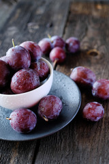 Fresh violet plums at dark wooden table background