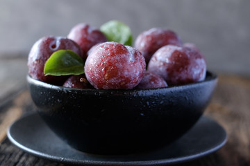 Fresh violet plums at dark wooden table background