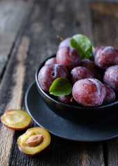 Fresh violet plums at dark wooden table background