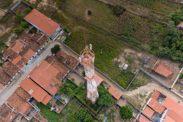 Mobile Antenna in a small city surrounding by small houses and rocks 