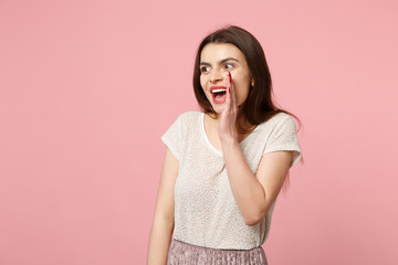 Excited young woman in casual light clothes posing isolated on pink background, studio portrait. People lifestyle concept. Mock up copy space. Screaming with hand gesture near mouth, looking aside.