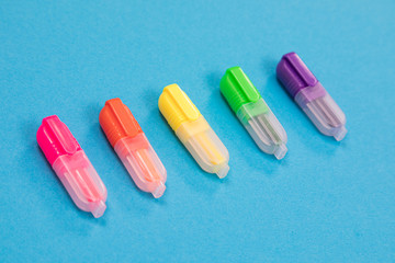 Five small multicolored highlighters on azure background isolated