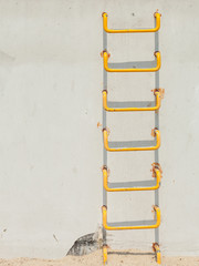 Yellow ladder on light grey conrecete wall
