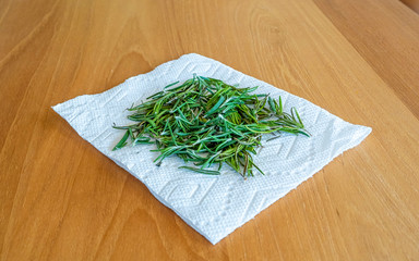Aromatic Fresh rosemary drying on a paper towel on a hardwood background 