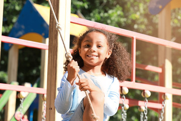 Cute African-American girl having fun on playground outdoors