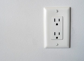 Isolated North American power outlet plug in socket on a white wall background Type B style