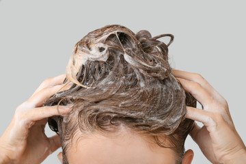 Naklejka premium Beautiful young woman washing hair against grey background, closeup
