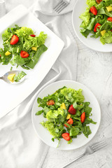 Plates with fresh tasty salad on light table