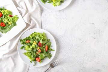 Plates with fresh tasty salad on light table