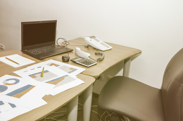business graphs, laptop, calculator and office phone on the table. Work in process