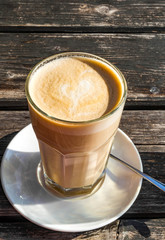 Glass cup of coffee latte with beautiful heart shape, wooden table