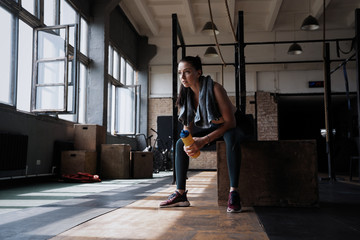 Fitness woman sitting on a box at gym after her workout.