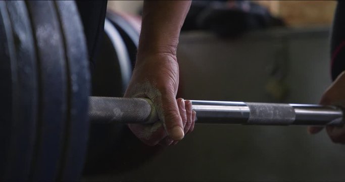 Hands grabbing deadlift bar and lifting