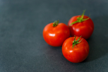 Fresh delicious tomatoes. Red tomatoes on a gray background. Tasty many vegetarian vegetables on a beautiful stone background.