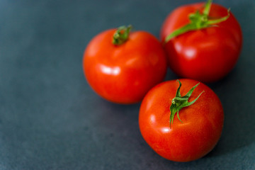 Fresh delicious tomatoes. Red tomatoes on a gray background. Tasty many vegetarian vegetables on a beautiful stone background.
