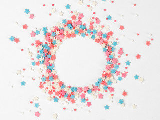Festive border frame of colorful pastel sprinkles on white background with copy space in center....