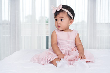 baby in pink dress on bed