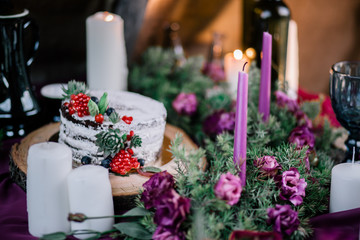 Delicate wedding white cake decorated with pomegranate and succulent surrounded by flowers and candles.