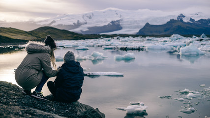 Two girl friends discussing photography at a cliff facing the Jökulsárlón Glacial Lagoon in...