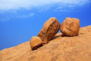 Red bald granite peak, blue sky, white cloud background, three round ancient orange stones, natural yellow rock, Swakopmund, Spitzkoppe mountains, Naukluft national park, Namib Desert, Namibia, Africa