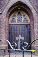 wooden gothic church door behind an iron gate with cross