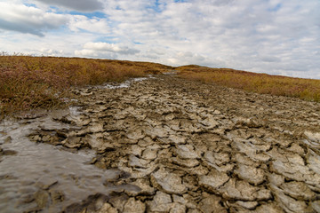 Mud volcano on the Crimean peninsula in sunny weather with clouds on the sky, shot during the season of golden autumn. Yellow-golden brown.