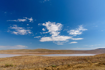 Fototapeta na wymiar Koyashsky, salty, lake on a sunny day with clouds on the sky, shot during the season of golden autumn. Yellow-golden brown.