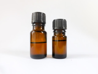 Two brown bottles with essential oils of different sizes on white background