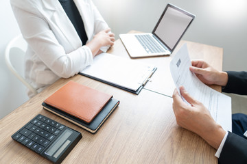 Business consulting candidate employee in suit looking skeptical reading a resume, hr speaking at job interview and recruitment concept.