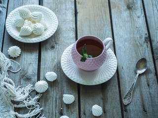 Morning tea. Ceramic decorative vase. Meringue cookies, composition on a wooden unpainted table, a piece of knitted white tablecloth
