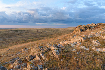 Dawn on a mountain in the steppe of the Opuksky nature reserve with yellow grass, with clouds on the sky, shot during the season of golden autumn. Yellow-golden brown.