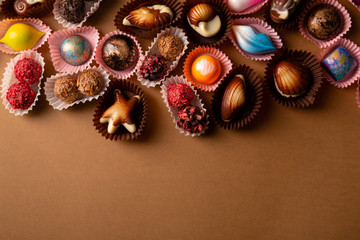 Chocolate bonbons set on brown background top view and copy space