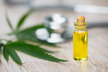 CBD Hemp oil, marijuana plant and cannabis oil on wooden table, medical marijuana oil concept
