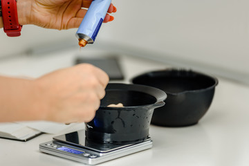 Closeup of hairdresser squeezing hair coloraunt in bowl with dye