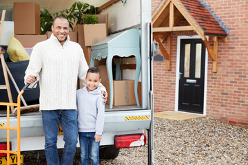 Portrait Of Father And Son Unloading Furniture From Removal Truck Into New Home