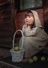 Dreaming girl with apples on a summer evening near the old house.