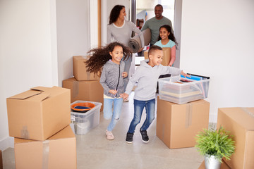 Smiling Family Carrying Boxes Into New Home On Moving Day
