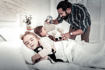 Focus on sleeping girl with turned back to her sister and father
