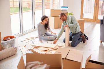 Couple In New Home On Moving Day Putting Together Self Assembly Furniture