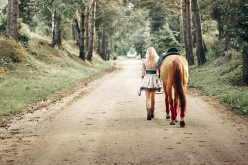 beautiful girl goes on the road with a horse.
