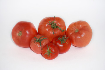 red tomato fruits of different sizes on a white background