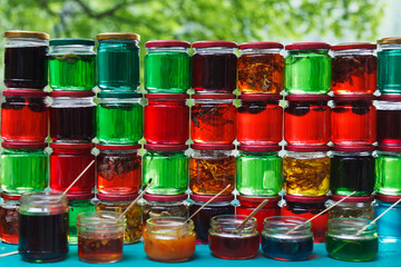 Green, red and yellow jars with honey.