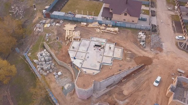 View from above of construction materials ( wooden boards, rocks, bricks) and people working on the building site and pouring concrete. Clip. Process of new building construction
