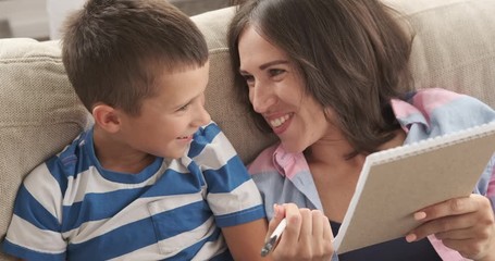 Mother with son having fun while writing to do list in notepad
