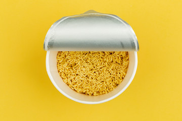 A plate of noodles on a yellow background. Top view.