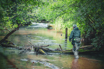 The fisherman moves along a beautiful stream. Trout fishing.