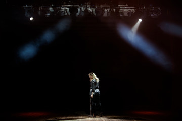 A young woman singer on stage during a concert view from the back.