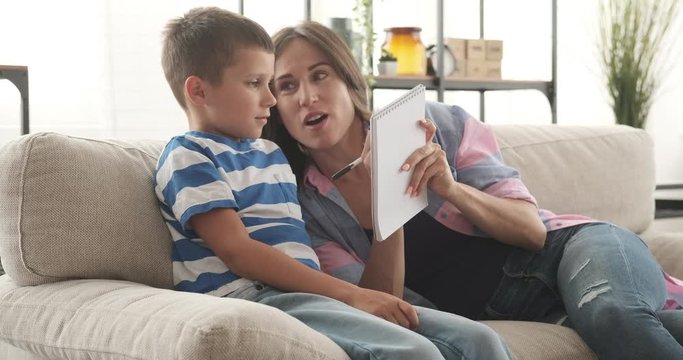 Happy mother with her son planning and writing to do list in notepad